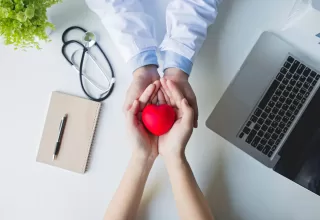 Top view .doctor and patient hands holding red heart on white table, health care love, give, hope and family concept, world heart day,world health day